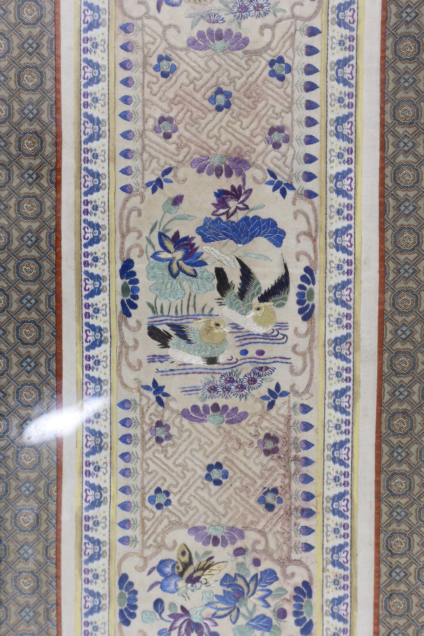 A framed pair of Chinese embroidered sleeve bands using Chinese knot and a another single framed sleeve band, pair 61.5 cms high x 26.5 wide.